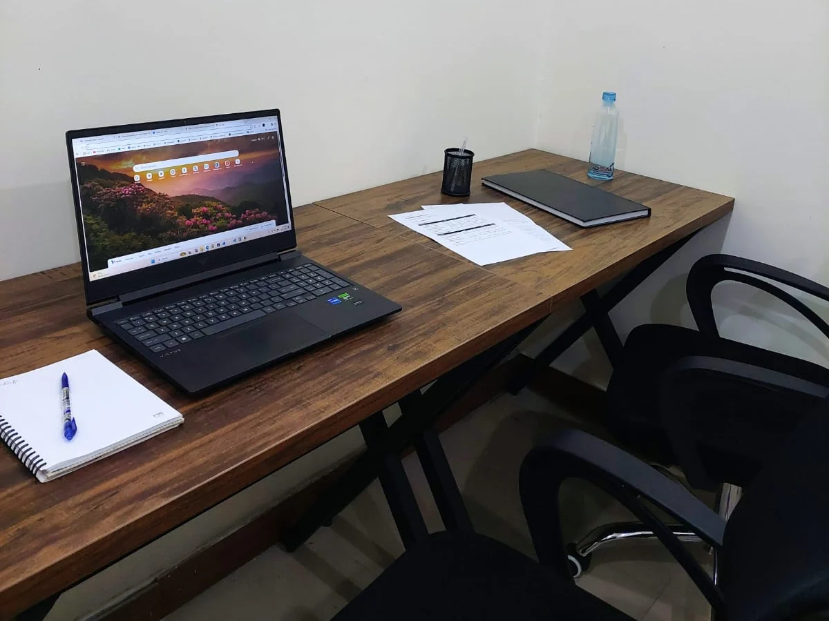 A desk in the Solinovo office: an open laptop, a ruled notebook and pen, printed pages, and two chairs pulled up to it.