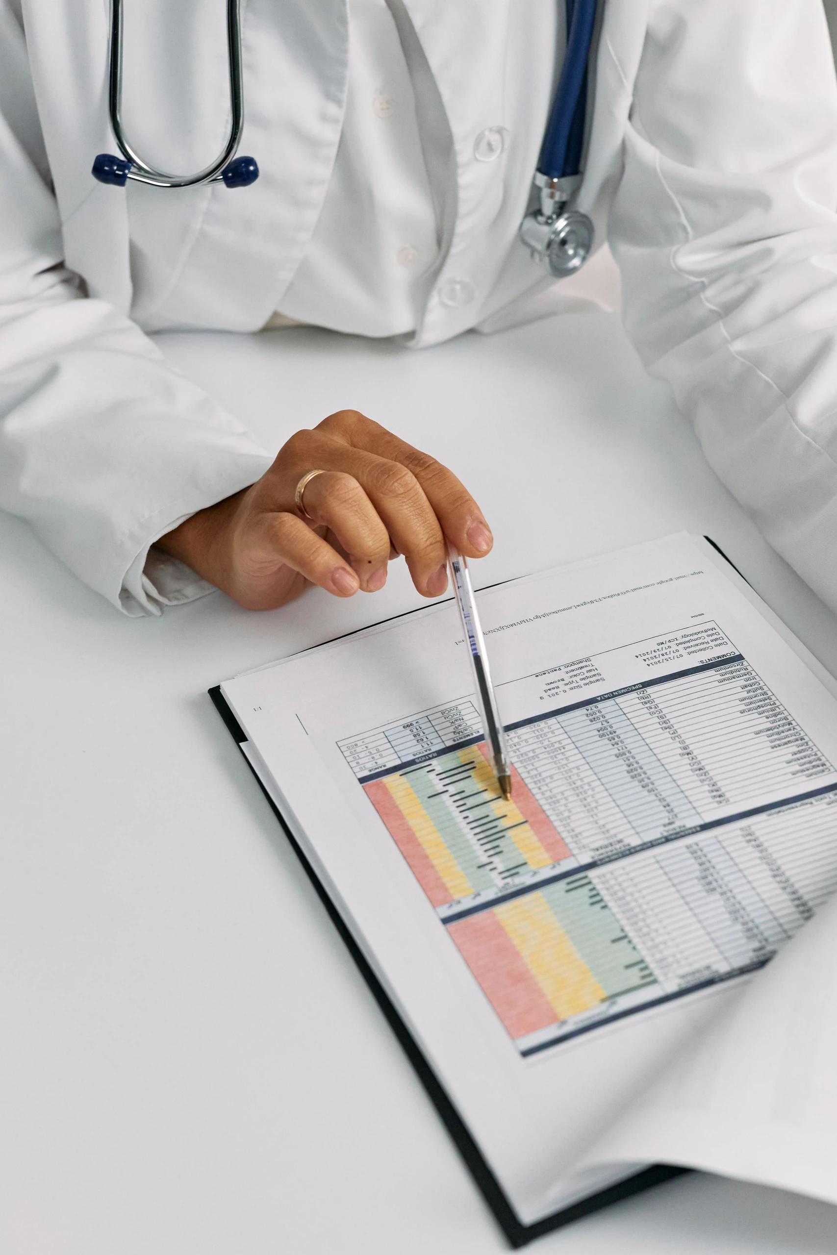 A doctor reviewing a patient chart with a pen.